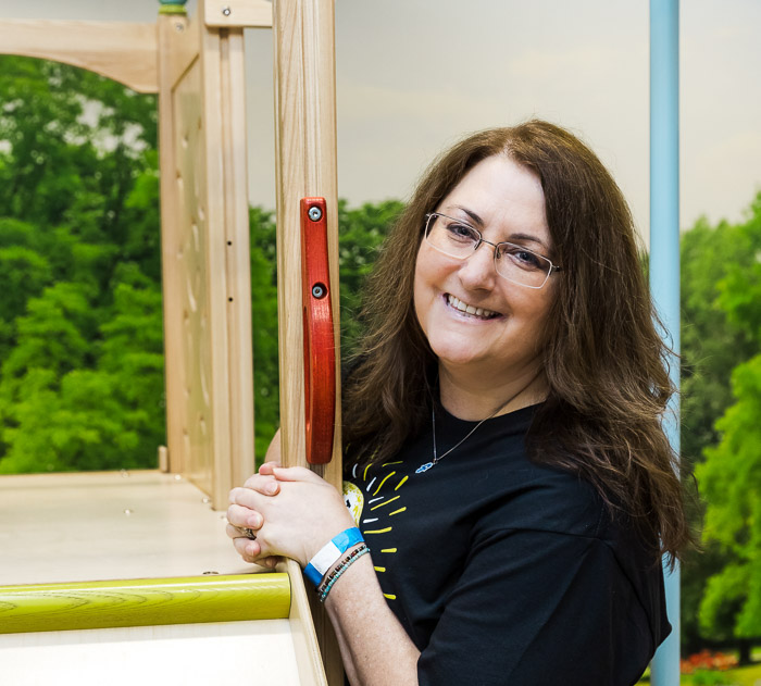 Lisa Kunz leans against a wooden slide in a children's indoor playground