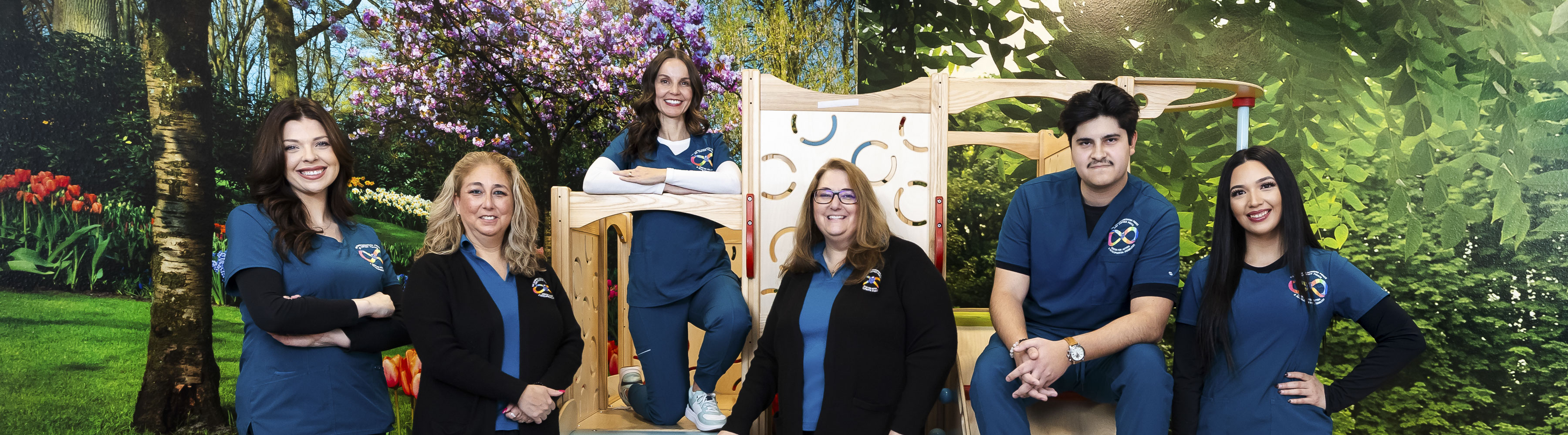 Employees of the center take a group photo in their branded scrubs in the therapy park climbing gym.